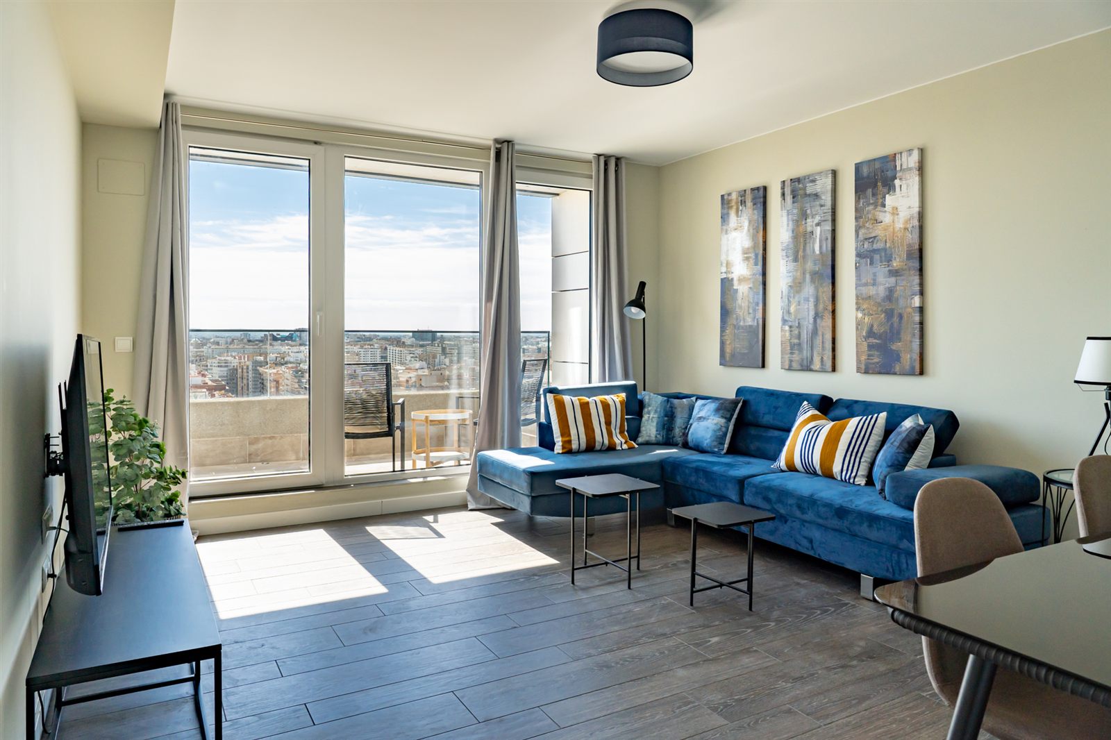 Salón con sofá azul y ventanales de Torre Zaragoza